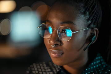Smart business woman working with computer while talking with earphone sitting in modern startup...