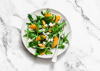 Fruit salad with tangerines, green salad mix and gorgonzola on a light background, top view