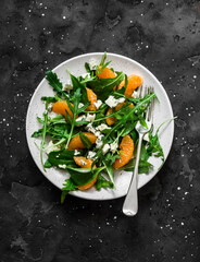 Fototapeta na wymiar Fruit salad with tangerines, arugula and gorgonzola on a dark background, top view