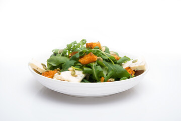 Vegetable salad with pumpkin, arugula and blue cheese in a plate on a white background