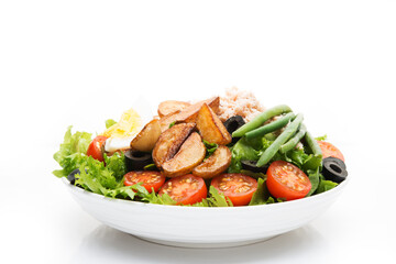 A plate of nicoise salad with tuna and potatoes isolated on a white background