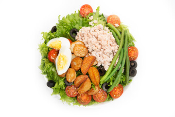 A plate of nicoise salad with tuna and potatoes isolated on a white background