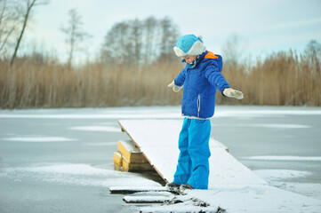 A child in danger on thin ice in winter. The boy is ice skating on a frozen lake.