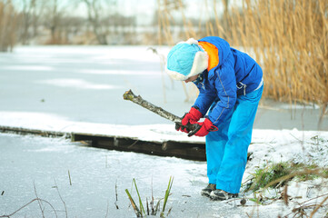 Fototapeta A child in danger on thin ice in winter. The boy is ice skating on a frozen lake. obraz