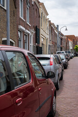 Street parking of cars in old Dutch town Zierikzee with old small houses and streets