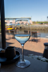 Glass of white wine served in cafe with view on harbour of Harlingen, vacation in Friesland, Netherlands