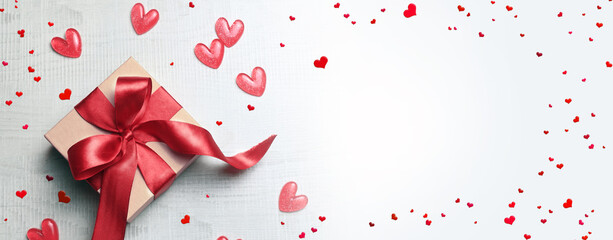Top view photo of valentine's day decorations white gift box with red ribbon bow and small hearts on isolated light background. - obrazy, fototapety, plakaty