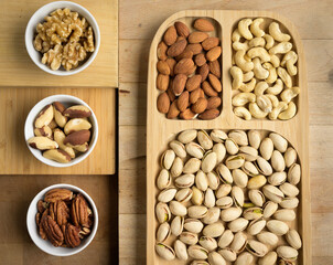 Different nuts and bowls closeup on a wooden table and brown background. Peanut, nut, cashew, almond, hazelnut, pistachio