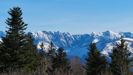 Montagne avec de la neige, arbre, épicéa, sapin, un ciel bleu, du soleil, rocher abrupte.