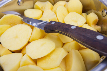 Kitchen knife with chopped peeled raw potatoes ready for cooking. Home food.