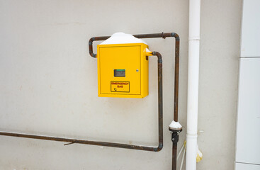 Metal anti vandal box with natural gas meter gauge and pipeline on the wall. Gas distribution for heating apartments in winter.