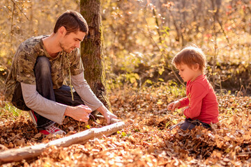 father and son saw a log with a wire saw in camp autumn, spending time together