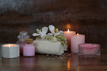 Spa-Arrangement mit Kerzen ,Orchidee, Handtuch und Pflegeprodukte.
