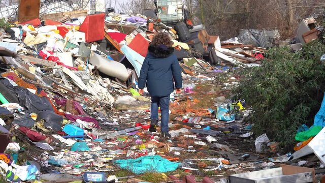 Europe, italy , Milan 7-year-old boy walks in the middle of an illegal and abusive landfill of polluting waste of various kinds - climate change, global warming and air pollution of the planet earth