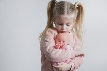 Cute little girl playing with her baby doll