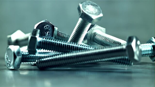 A bunch of bolts fall on the table. On a gray background.Filmed is slow motion 1000 fps.