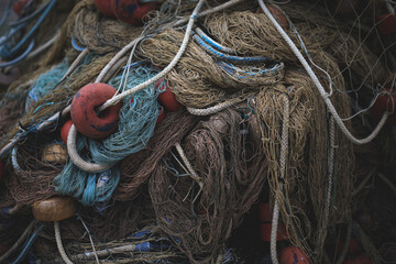Various fishing nets piled up in a box in a harbor made from different old and wrinkled ropes and threads