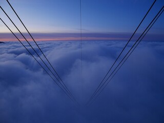 Cables of Hoher Kasten cable car and fog blanket at sunset. Alpstein, Appenzell, Switzerland. 