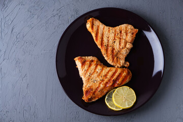 Grilled turkey fillet on a plate on a dark background