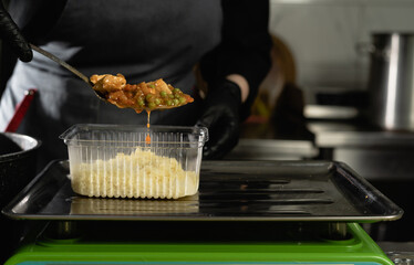 food delivery in the restaurant. Close-up of a gloved chef's hand weighing a batch of rice on an...