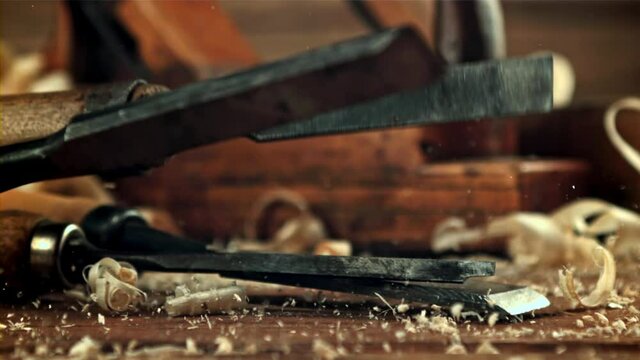 Chisels fall on a table of sawdust. On a wooden background. Filmed is slow motion 1000 frames per second. High quality FullHD footage