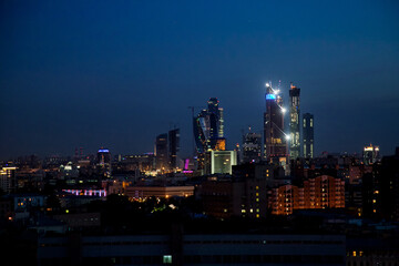 Fototapeta na wymiar Evening (night) illuminated towers of Moscow City. Buildings construction on deep blue sky. Panoramic photo.