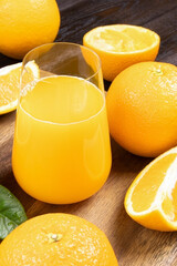 Fresh orange juice in a glass on a wooden background. Fresh Orange fruits with green leaves. Healthy vegan food. Vitamins food.Ripe oranges.Flat lay. Vertical orientation.
