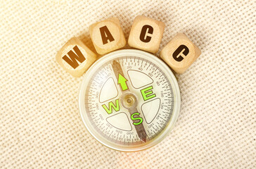 On the table is a compass and cubes with the inscription - WACC