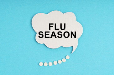 On a blue table are pills and a white plate with the inscription - FLU SEASON
