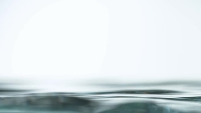 Super slow motion of water surface on light blue background. Filmed on high speed cinema camera, 1000 fps.