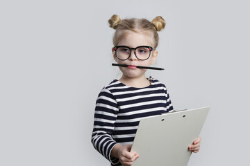 Portrait of adorable little girl with reading glasses, pen and paper. Business and education...