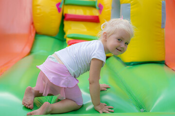 Fototapeta na wymiar The little one crawls and plays on a children's inflatable trampoline in the park.