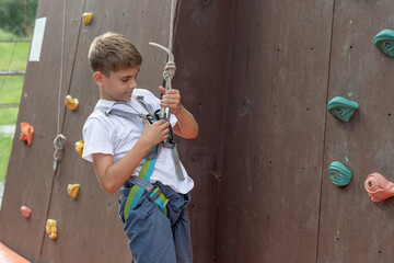 A boy unhooking a safety rope after descending a climbing wall at a sports park climbing wall.