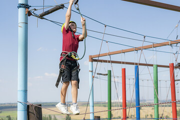 A boy on a cable car clings to a safety rope in a sports rope park.