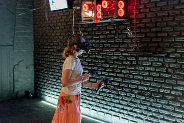 A girl in a VR helmet plays games in the computer room and controls joysticks.