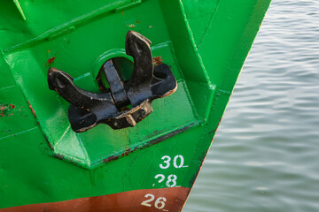 Ship anchor, vessel at the quay, green background