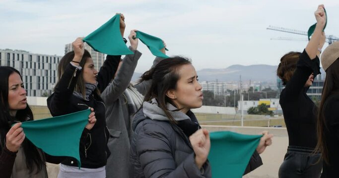 women's march with green scarves shouting slogans