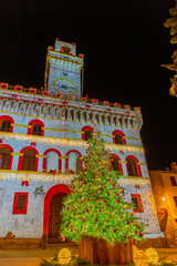 The Palazzo Comunale di Montepulciano stands on the western side of the Piazza Grande decorated with Christmas lights and a Christmas tree. - obrazy, fototapety, plakaty