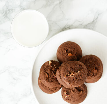 Overhead View At Stack Of Chocolate Chip Cookies With Glass Of Milk On White Background