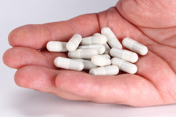 Man hand full of white tablets of medicine