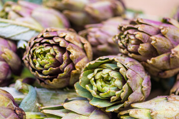 Fototapeta premium Fresh green artichokes with green leaves in a street food market, close up