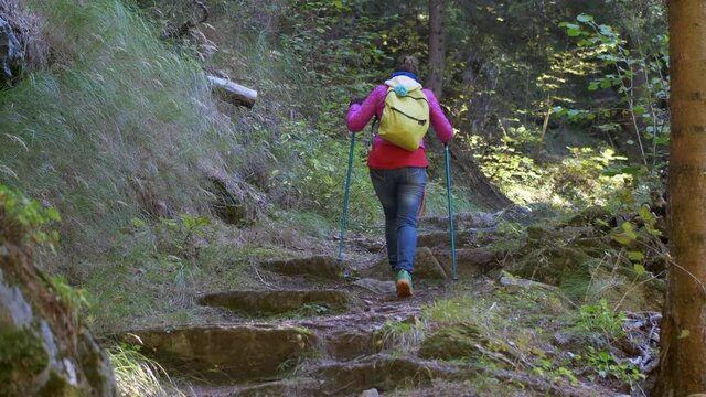 Woman climbs a steep mountain path. Playing sports. Slow motion 4K