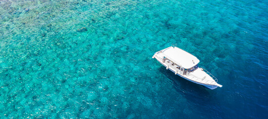 Luxury small yacht anchoring in shallow water. Aerial view of tropical island beach holiday yacht...