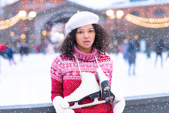 Close-up, pensive African American girl on the ice skating rink for a walk in winter. The portrait froze, young. Dark-skinned black woman with curly skates.