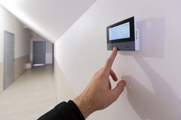 The air conditioning and heating control panel for the apartment and office is located on a white wall - obrazy, fototapety, plakaty