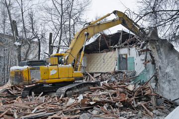 Building demolition. Excavator breaks old two-storey house. Industrial cityscape with destroy process.