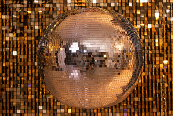 silver disco ball on a wall of sequins
