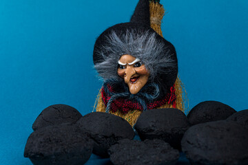 Epiphany holiday concept. Witch Befana and coal pieces for naughty kids on blue background. Copy...