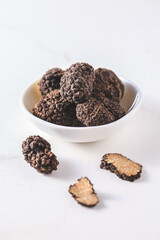 Black truffle in bowl on white background