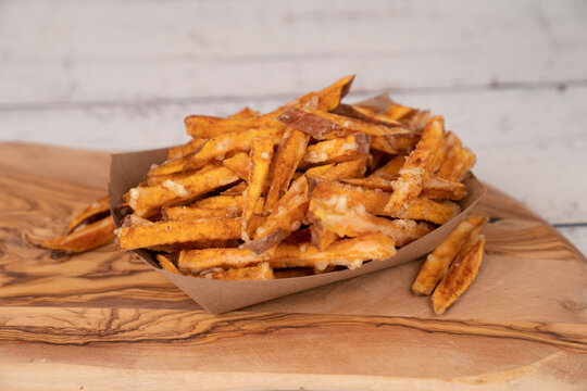 Sweet potato fries on paper container in wood board